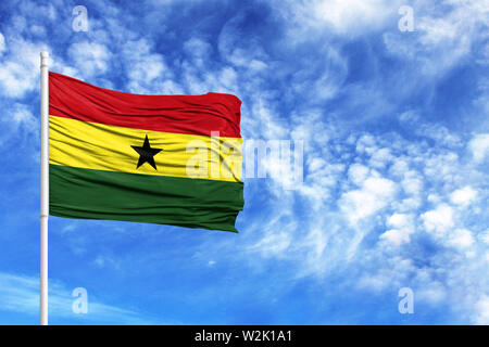 National flag of Ghana on a flagpole in front of blue sky Stock Photo