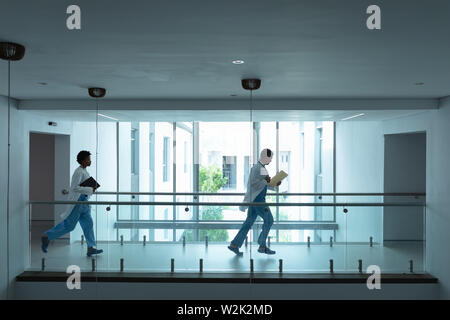 Female and male doctors running in the corridor at hospital Stock Photo