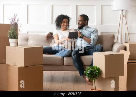 Smiling black couple use digital tablet on moving day Stock Photo