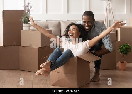 Happy african young couple riding in box on moving day Stock Photo
