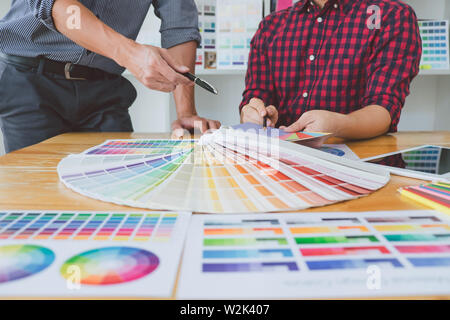 Team of Creative graphic designer meeting working on new project, choose selection color and drawing on graphics tablet with work tools and accessorie Stock Photo