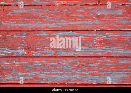 Abstract Rustic aged closeup of barn wood panel painted with red chipped and faded colour. horizontal slats with wood lines with  knot and texture Stock Photo