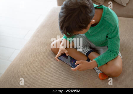 Boy playing game on mobile phone while sitting on sofa at home Stock Photo