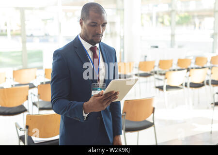 African-american businessman standing in conference room watching tablet Stock Photo