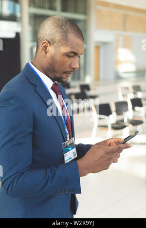 African-american male executive standing in conference room typing on smartphone Stock Photo