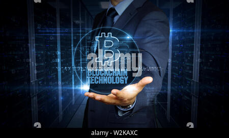 A businessman in a suit touch screen with bitcoin symbol hologram. Man using hand on virtual display. Cryptocurrency mining, blockchain, economy and v Stock Photo