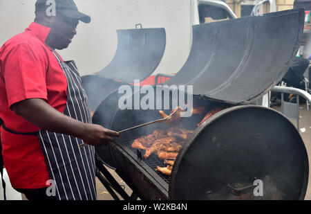 Man barbecuing chicken pieces on oil drum barbecue at Bristol St Pauls Carnival festival Stock Photo