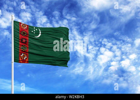 National flag of Turkmenistan on a flagpole in front of blue sky Stock Photo