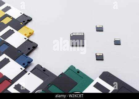 The evolution of digital data storage device. Floppy disks vs small memory cards. Isolated on a white background. Modern and retro technology. Stock Photo