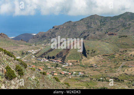 Valley of El Palmar in the Teno mountains with green slopes. In the center - volcanic hill like a sliced pie. Landmark of Tenerife, Canary Islands. Stock Photo