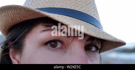 Portrait of a brown-eyed brunette in a hat looking straight into the camera with wide eyes