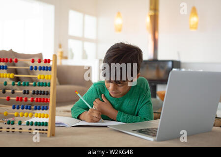 Boy using laptop while studying in living room at home Stock Photo