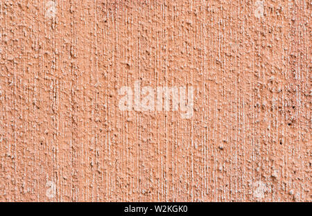 Macro close-up of plastered, painted, faded, rough and red, orange or peachy concrete or stone wall. High resolution full frame textured background. Stock Photo