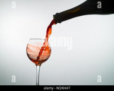 Red wine fills an empty wine glass on a white background Stock Photo