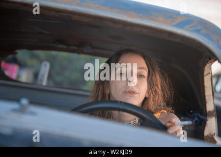 an attrrative young white woman in a car with a cigarette Stock Photo