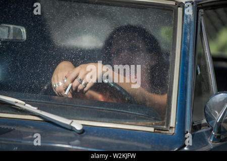 an attrrative young white woman in a car with a cigarette Stock Photo