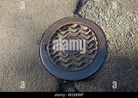 Sewer manhole on the urban asphalt road. Closeup photo Stock Photo