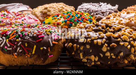 assorted donuts on wire rack on wooden cutting board Stock Photo