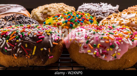 assorted donuts on wire rack on wooden cutting board Stock Photo