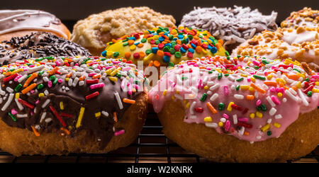 assorted donuts on wire rack on wooden cutting board Stock Photo