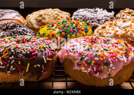 assorted donuts on wire rack on wooden cutting board Stock Photo