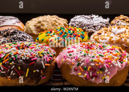 assorted donuts on wire rack on wooden cutting board Stock Photo