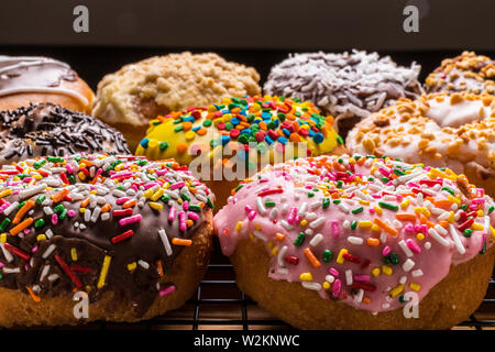 assorted donuts on wire rack on wooden cutting board Stock Photo