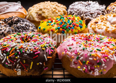 assorted donuts on wire rack on wooden cutting board Stock Photo