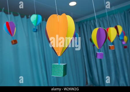 Origami made colorful air balloon cloud. Beautiful colored paper lanterns hanging on the ceiling as air balloons Stock Photo