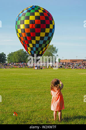 Small girl waving to hot air balloon about to ascend. Stock Photo