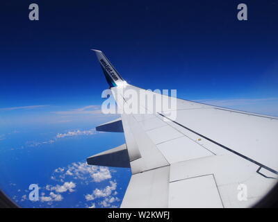 Left wing of a WestJet Boeing 737-800, with the WestJet.com logo on the wingtip. Beautiful sunny day high over the Caribbean.