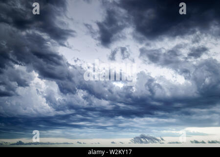 Background of dark stormy sky at summer evening. Dramatic skyscape with large gray clouds. Different cloud types and atmospheric phenomena. Stock Photo