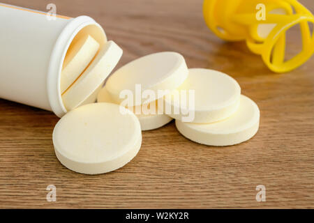 Soluble effervescent vitamin pills spilled out of a plastic bottle on a wood background. Vitamins and nutritional supplements. Healthcare and medical. Stock Photo
