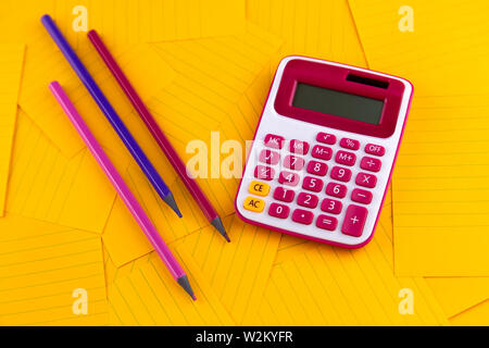 The concept of analysis, analytics, calculations. The calculator lies on orange sheets of paper with pencil. Stock Photo