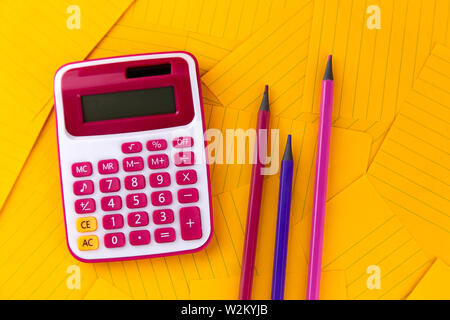 The concept of analysis, analytics, calculations. The calculator lies on orange sheets of paper with pencil. Stock Photo