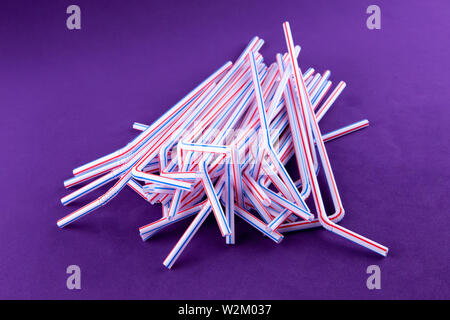 Coctail plastic tubes on blue purple background. Environmental concept. Ban single use plastic campaign. Copy space for text. Stock Photo