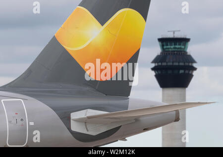 The tailfin of a Thomas Cook airliner taxiing along the runway in front of the control tower at Manchester Airport. Stock Photo
