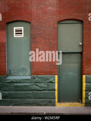 A green doorway and window on a red brick wall Stock Photo