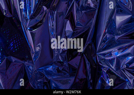 The background of crumpled holographic packaging film with an abstract pattern. Stock Photo