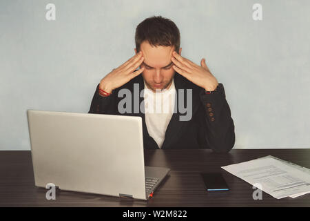 Serious frustrated businessman with closed eyes suffering from headache migraine at workplace, massaging temples, feeling tired exhausted, chronic Stock Photo