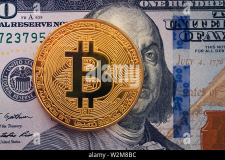 Golden bitcoin on hundred dollar bills with Franklin. Cryptocurrency background. Stock Photo