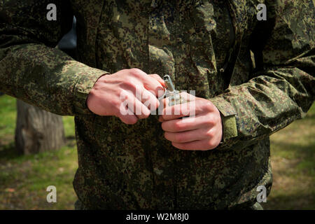 Military hand grenade throwing, pulling. Self-explosion. hands of the soldier pull the pin Stock Photo
