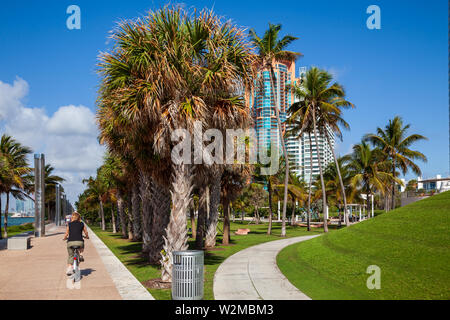 Model released female tourist riding a rental bicycle around Miami's South Beach on a sunny day. Stock Photo