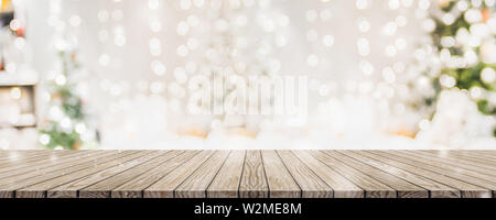 Empty woooden table top with abstract warm living room decor with christmas tree string light blur background with snow,Holiday backdrop,Mock up banne Stock Photo