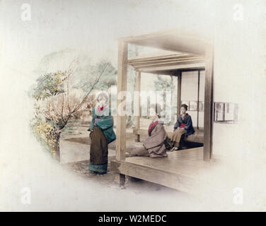 [ 1880s Japan - Three Japanese Women at a Residential Veranda ] —   Three women in kimono and traditional hairstyles at a traditional Japanese house, 1880s. Two women are sitting on the engawa, a veranda-like extension of the house.  19th century vintage albumen photograph. Stock Photo