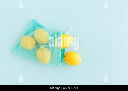 Reusable bag with lemons on blue background. Zero waste and plastic free shopping concept. Stock Photo