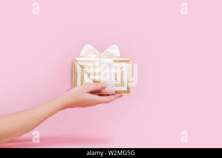 Womans hands holding gift or present box on pink pastel background. Stock Photo