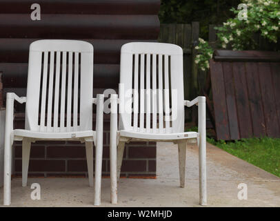 Two plastic garden chairs placed in the yard, countryside outdoor shot Stock Photo