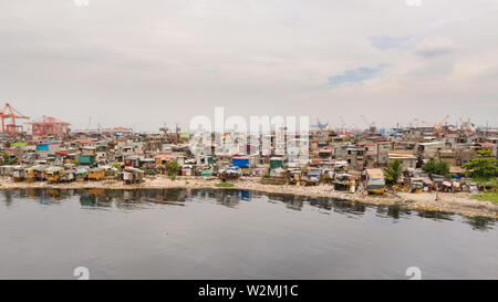 Slums in Manila near the port. Houses of poor inhabitants. A lot of garbage in the water, Philippines, top view. Stock Photo