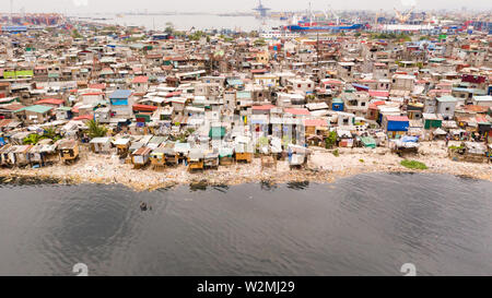 Slums in Manila near the port. Houses of poor inhabitants. A lot of garbage in the water, Philippines, top view. Stock Photo